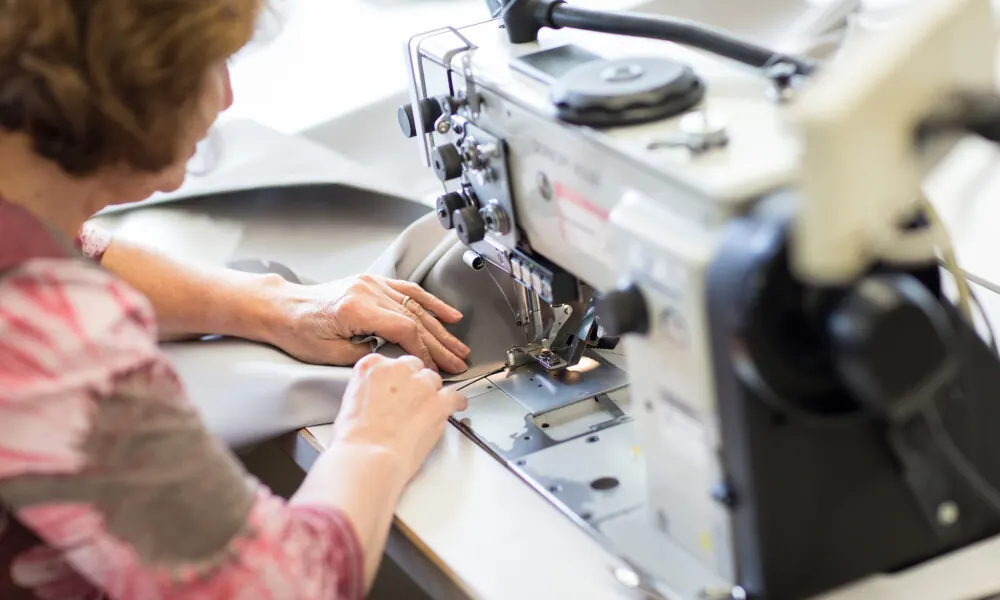 Naaister aan de industriële naaimachine bij Coolen