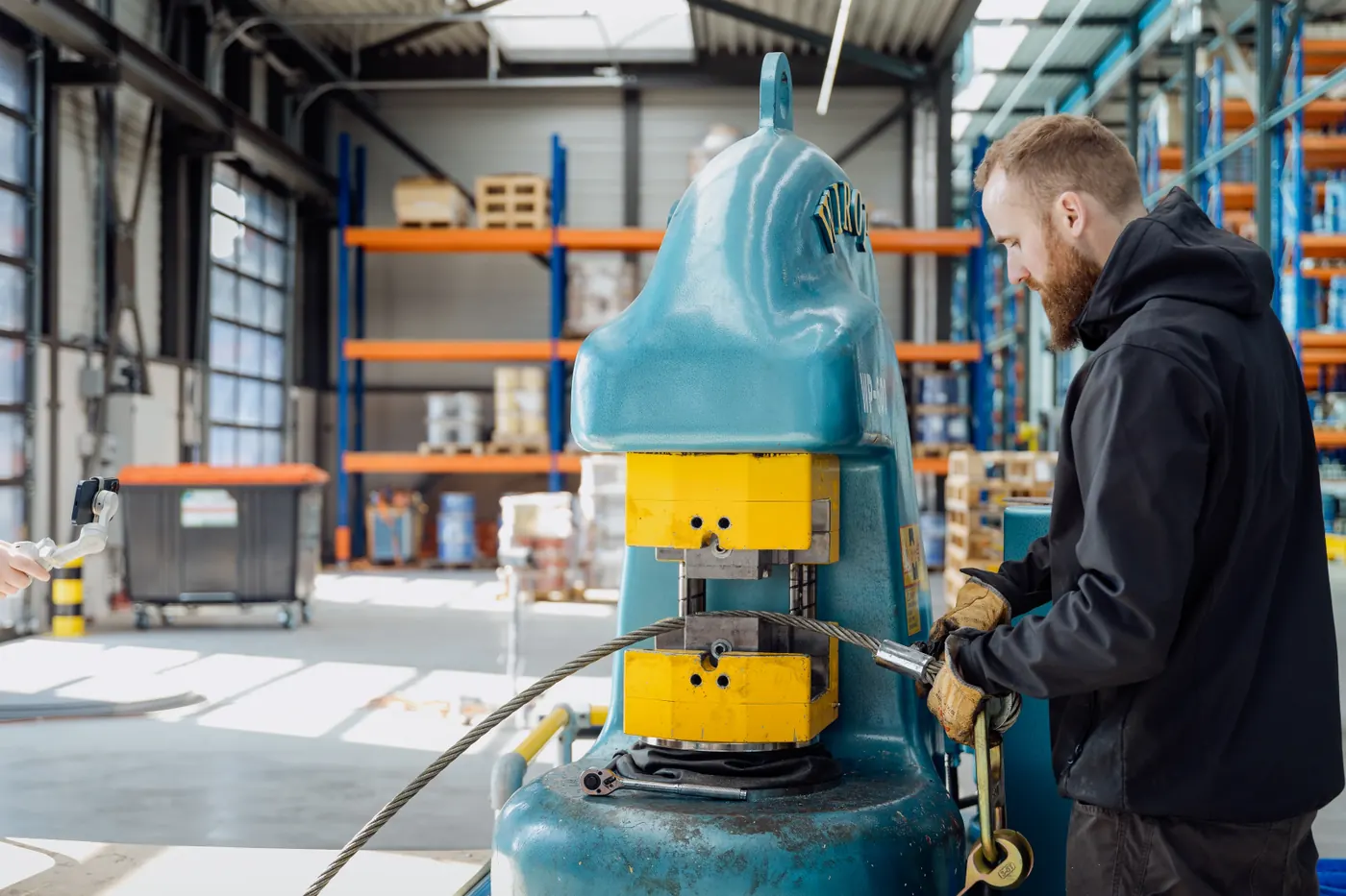 Medewerker aan een persmachine in de werkplaats van Louis Ruys
